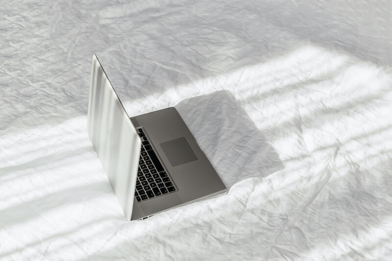 Laptop on white comforter on a bed