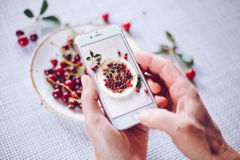 Using mobile phone to make a photo of a plate with berries